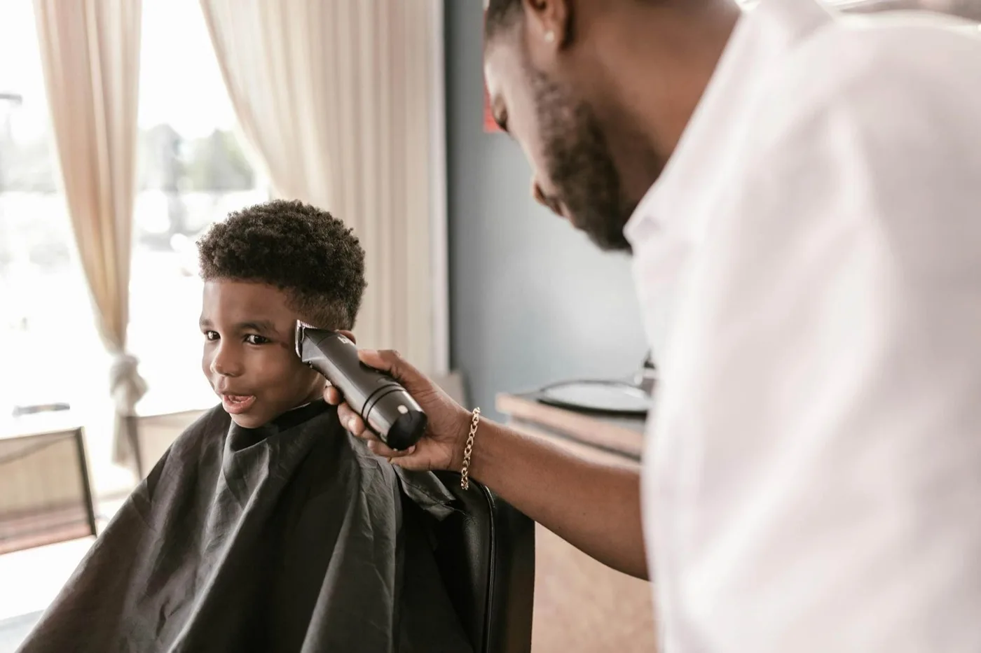 Barber giving a young client a haircut in his shop